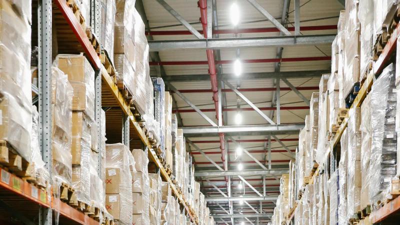 Pasillos de un centro de distribución con cajas en estanterías; cada movimiento ya lleva marca de tiempo en el ERP