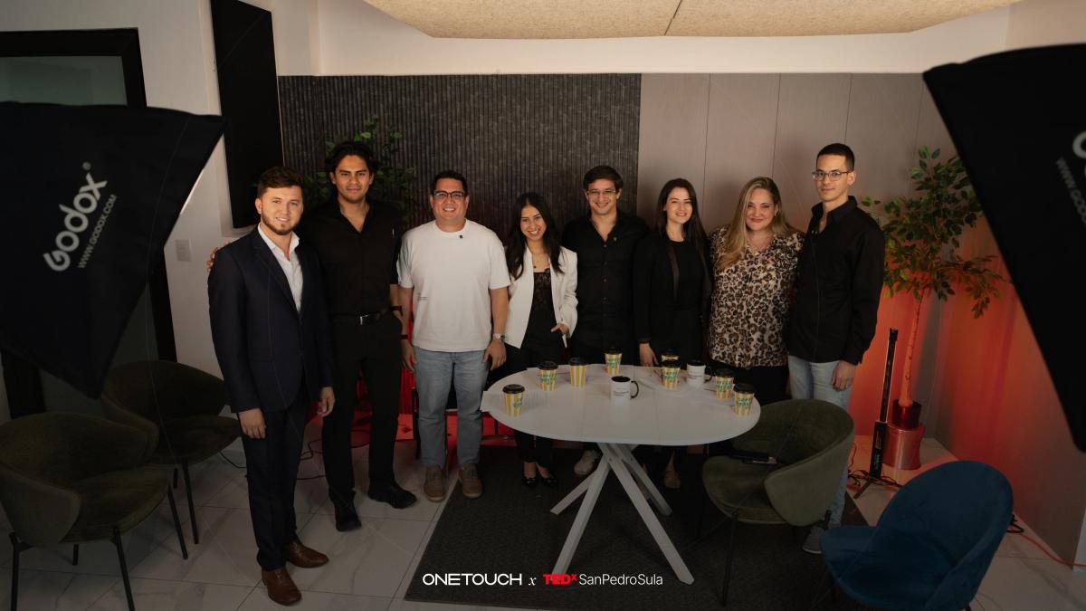 Equipo de Onetouch reunido en set de fotografía junto a una mesa blanca, anunciando la alianza con TEDxSanPedroSula 2026 bajo el lema "Reescribiendo el futuro".
