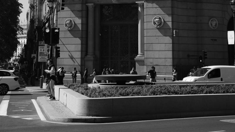 El edificio del Banco de España en la calle de Alcalá de Madrid, fotografiado en blanco y negro con el tráfico pasando por delante.