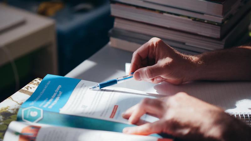Unas manos anotan con bolígrafo un documento impreso y añaden las preguntas que el brief no respondió.