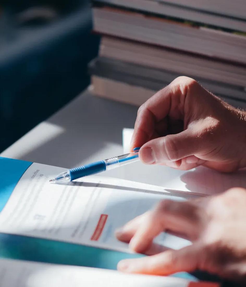 Hands annotating a printed document with a pen, adding the questions the brief did not answer.