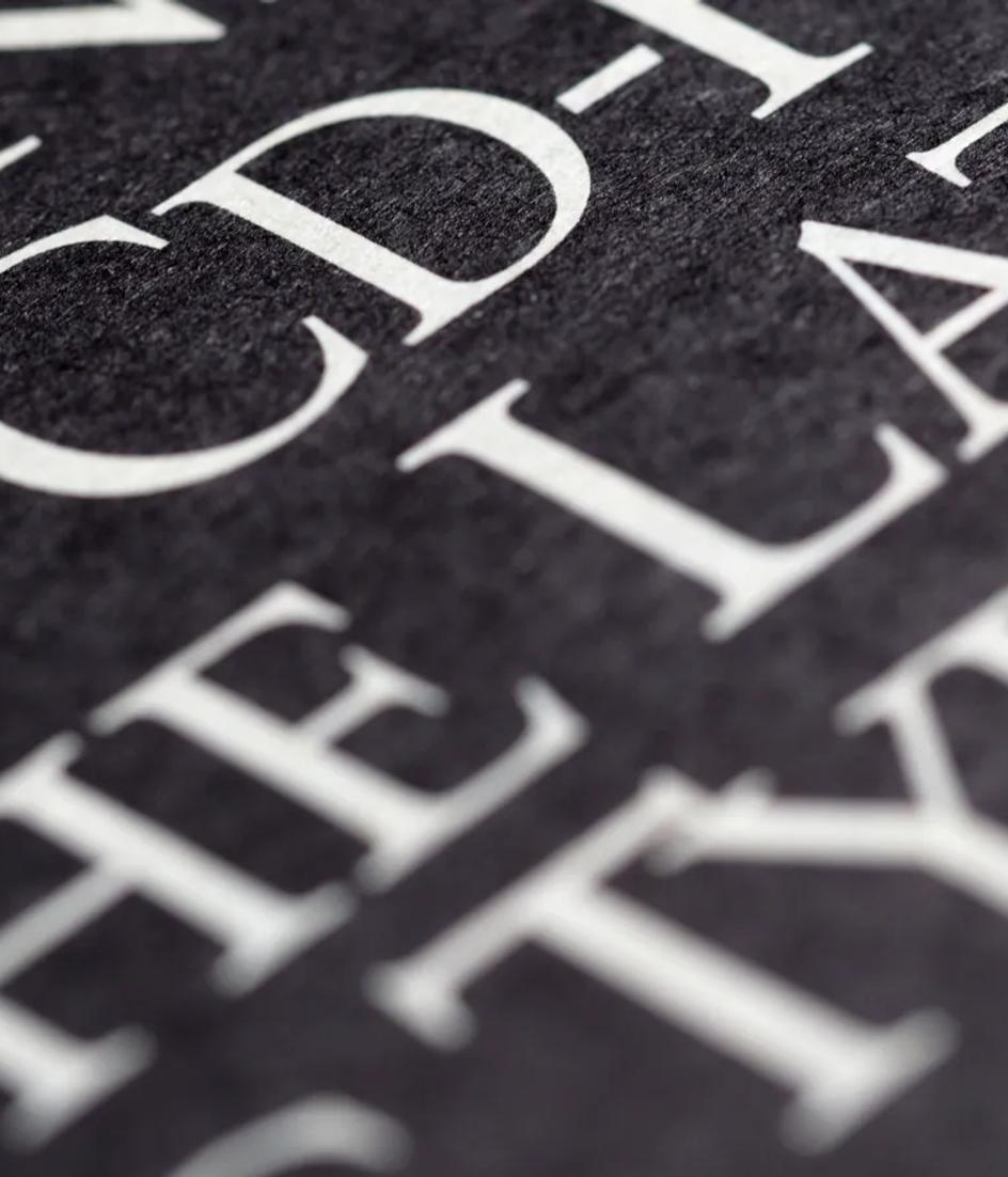 Bold white lettering printed on black paper, close enough to show how the counters hold at high contrast.