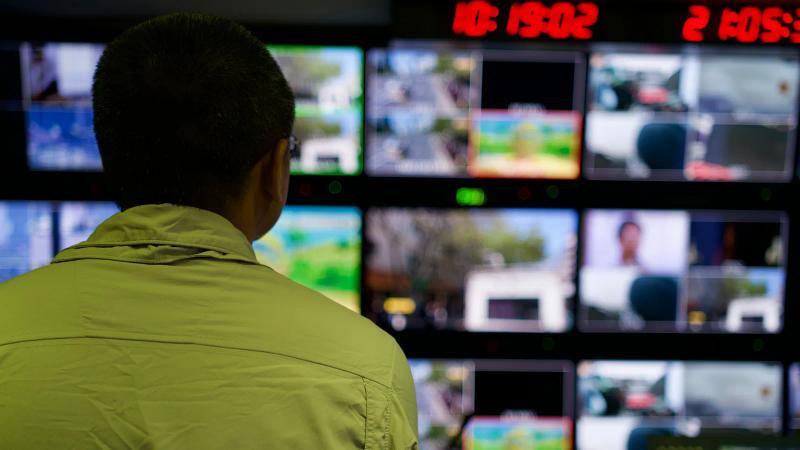 Un operador vigila una pared de monitores en una sala de control, cada pantalla con un proceso distinto en marcha