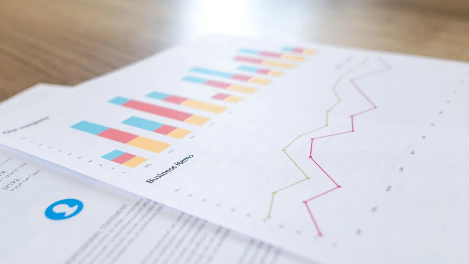 Printed line and bar charts spread on a desk, the monthly calibration review that compares predicted rank against what actually closed