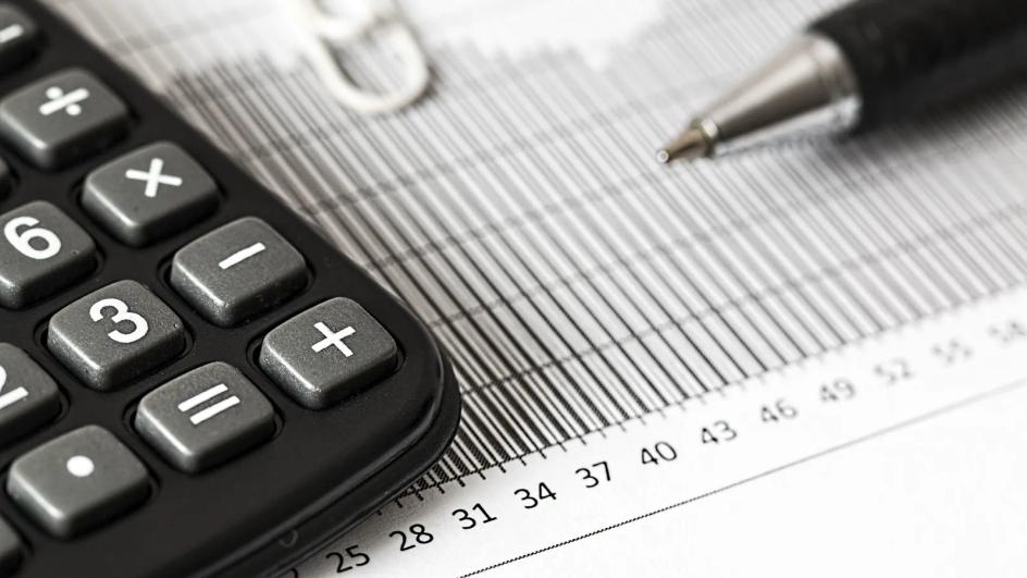 A calculator and a ballpoint pen resting on a printed bar chart, the tools a buyer uses to compare two quotes.