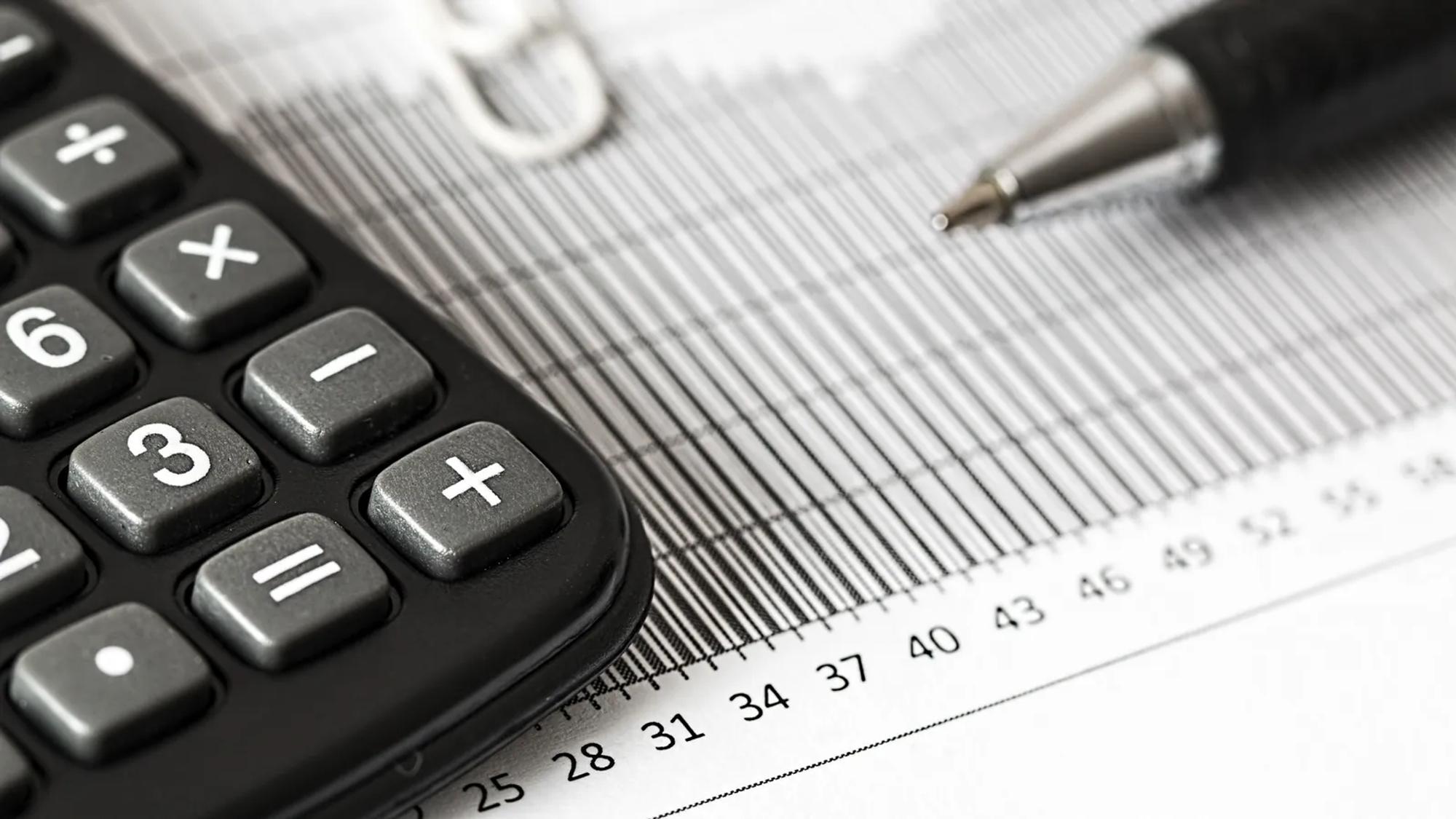 A calculator and a ballpoint pen resting on a printed bar chart, the tools a buyer uses to compare two quotes.