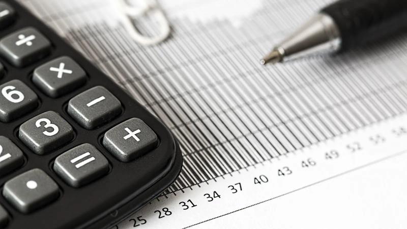 Una calculadora y un bolígrafo sobre un gráfico de barras impreso, las herramientas con las que se comparan dos presupuestos.