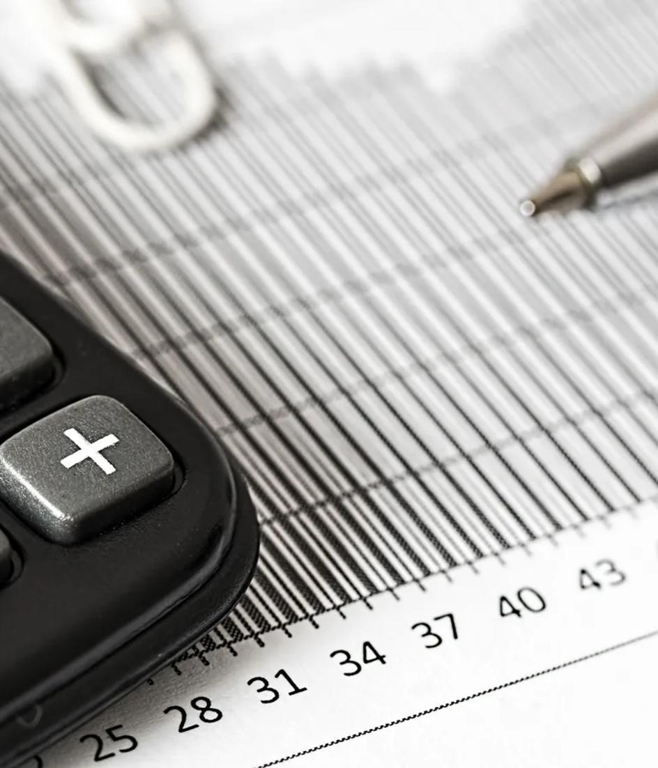 A calculator and a ballpoint pen resting on a printed bar chart, the tools a buyer uses to compare two quotes.