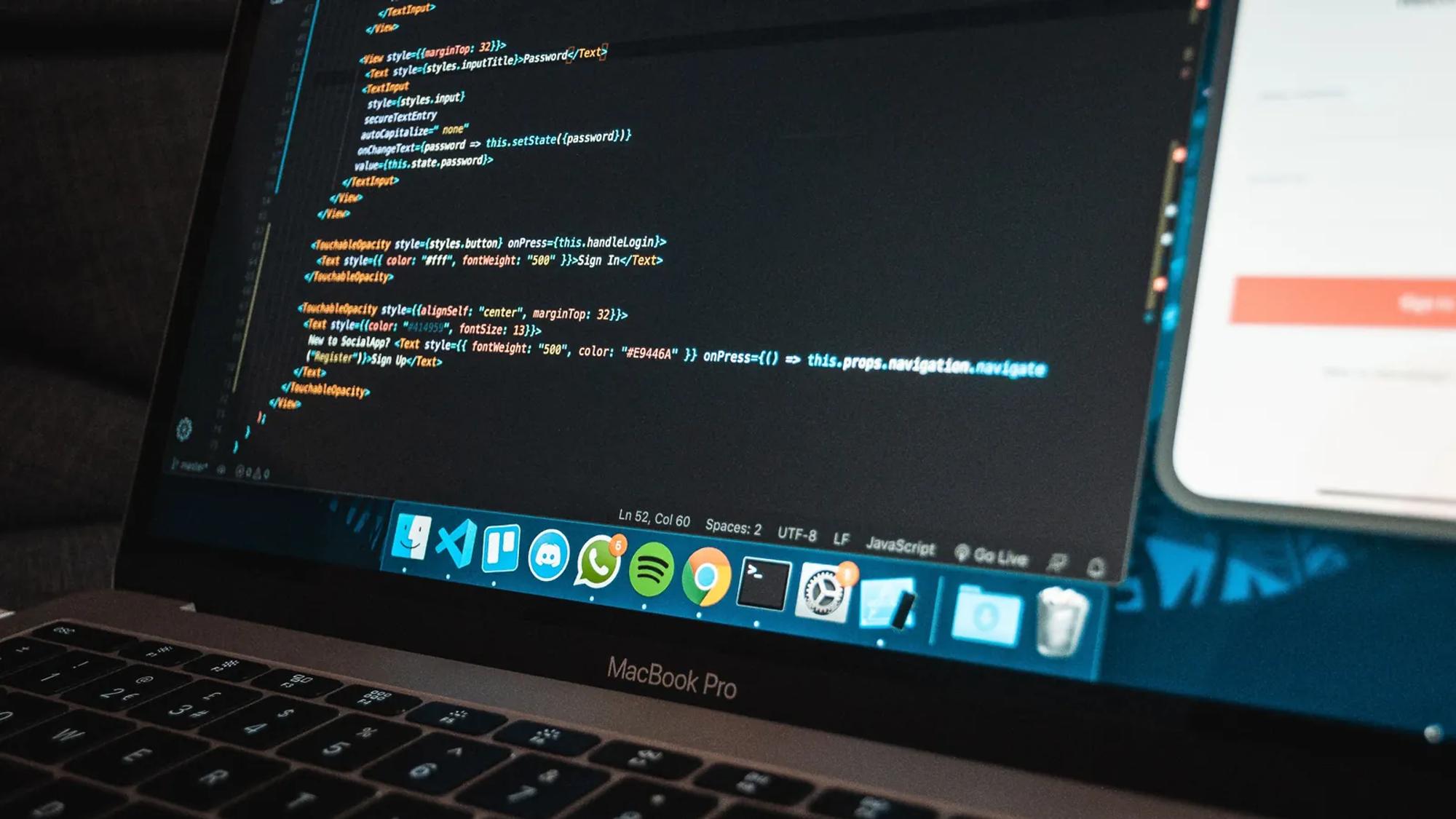 Primer plano de un portátil sobre una mesa con código de programación en la pantalla, en una oficina