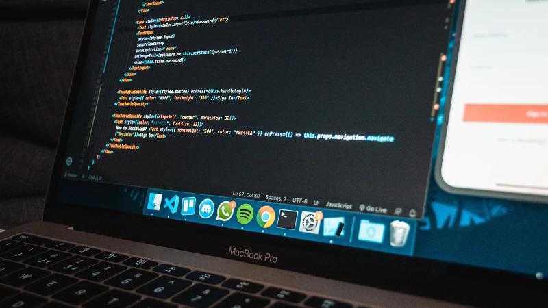 Primer plano de un portátil sobre una mesa con código de programación en la pantalla, en una oficina