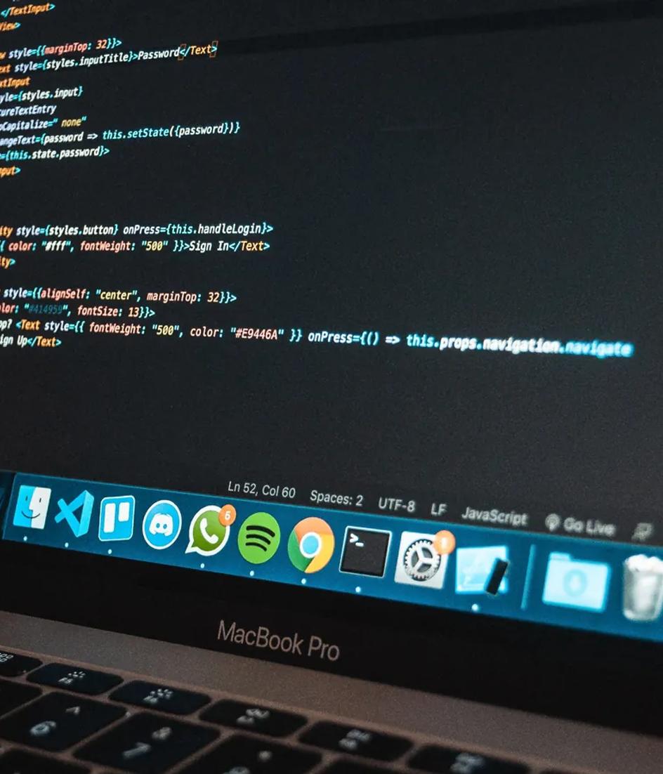 Primer plano de un portátil sobre una mesa con código de programación en la pantalla, en una oficina