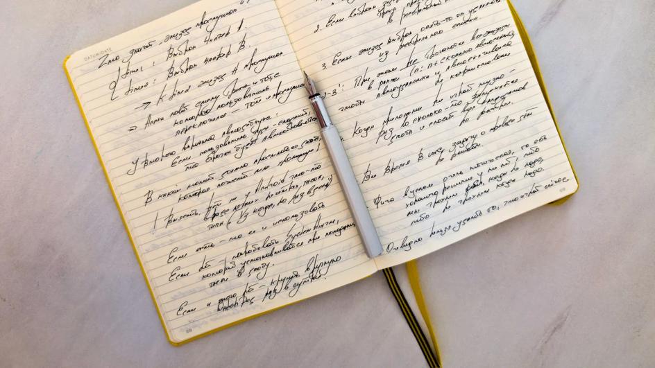 An open notebook filled with handwritten notes and a pen resting across the page, the format an AI approval sheet should fit into.