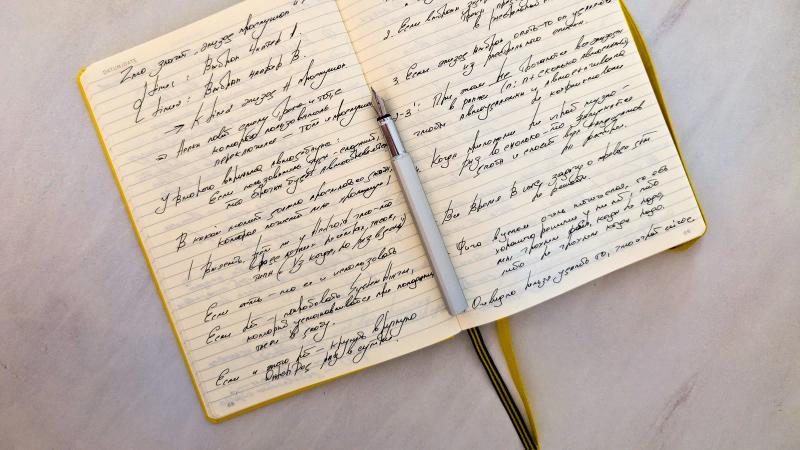 Un cuaderno abierto con notas escritas a mano y un bolígrafo sobre la página, el formato en el que cabe una hoja de aprobación de IA.