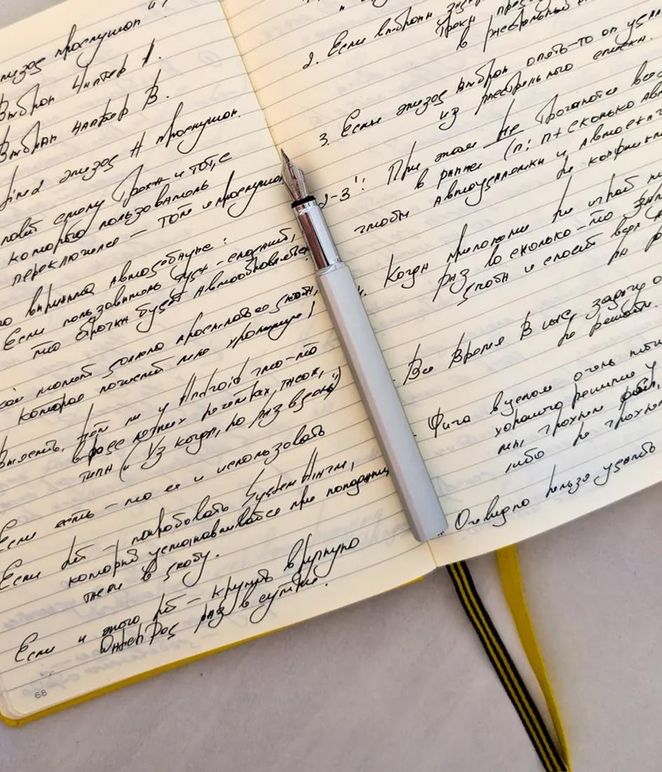 An open notebook filled with handwritten notes and a pen resting across the page, the format an AI approval sheet should fit into.