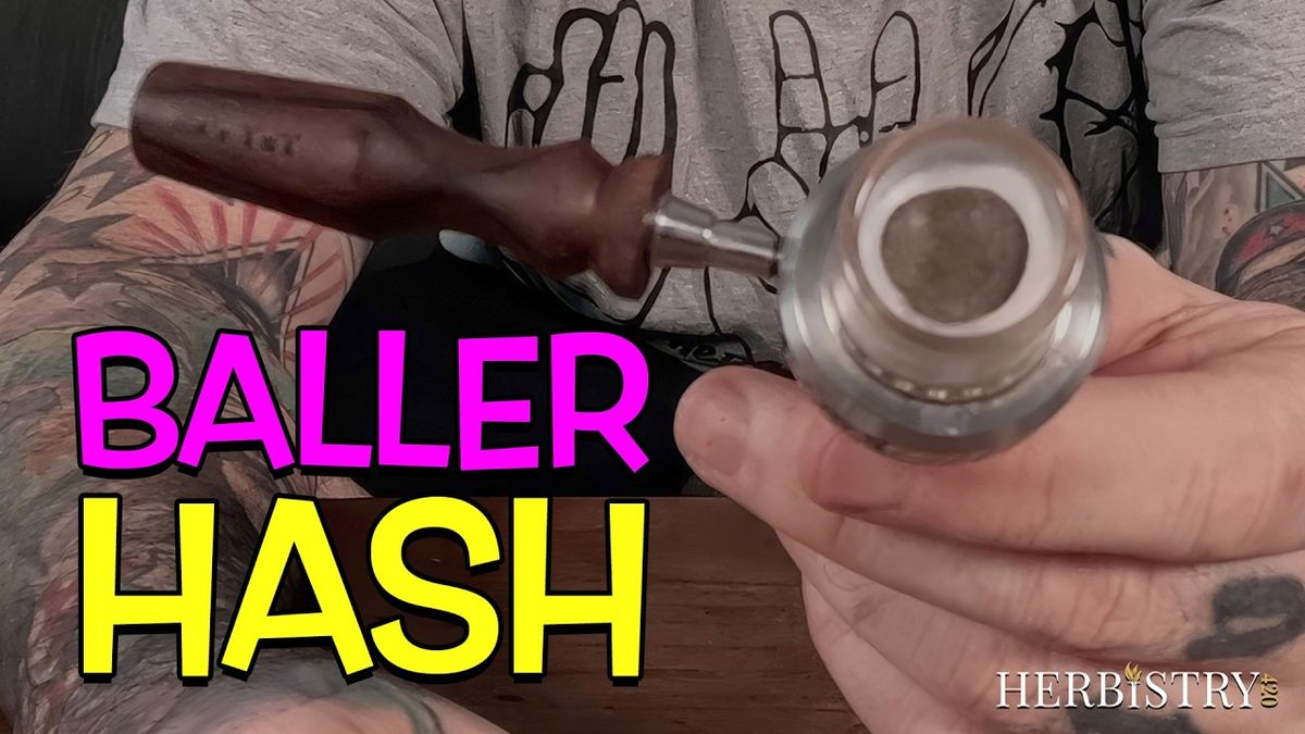 Hand holding the Universal Baller bowl loaded with a disc of hash, wooden handle attached