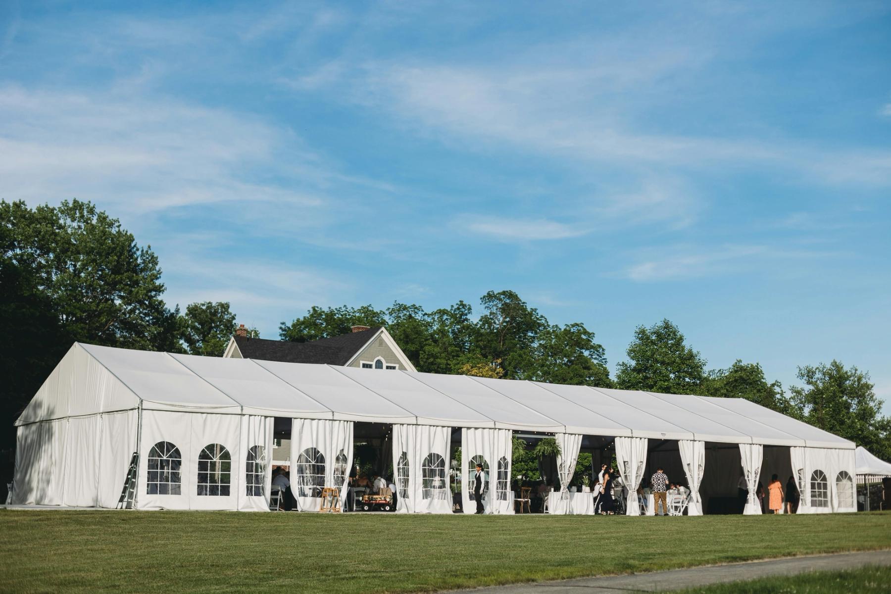 White frame tent set up in a backyard for an outdoor party in Caldwell New Jersey with round tables and chairs arranged underneath
