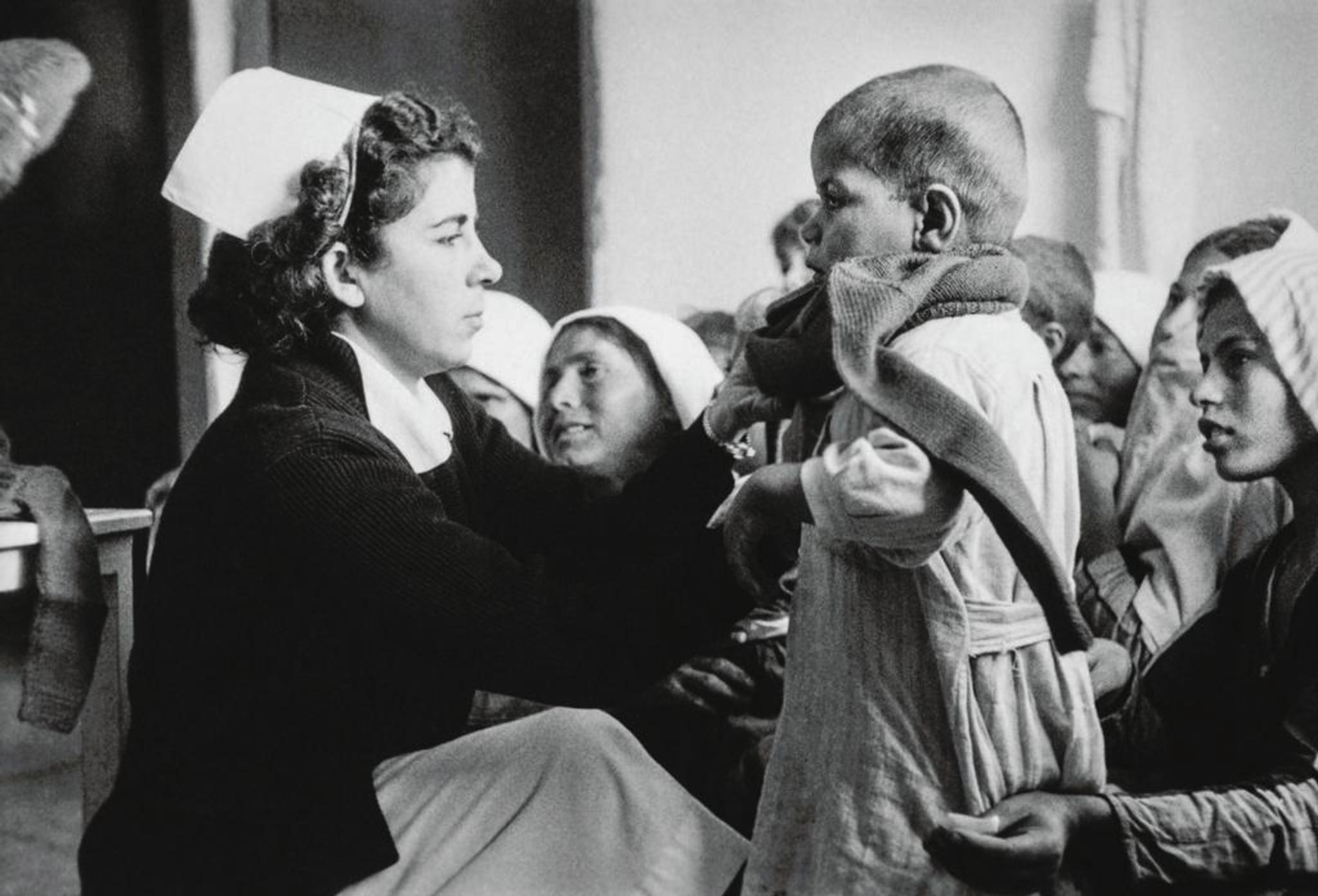 Nurse with a child and a group of women.