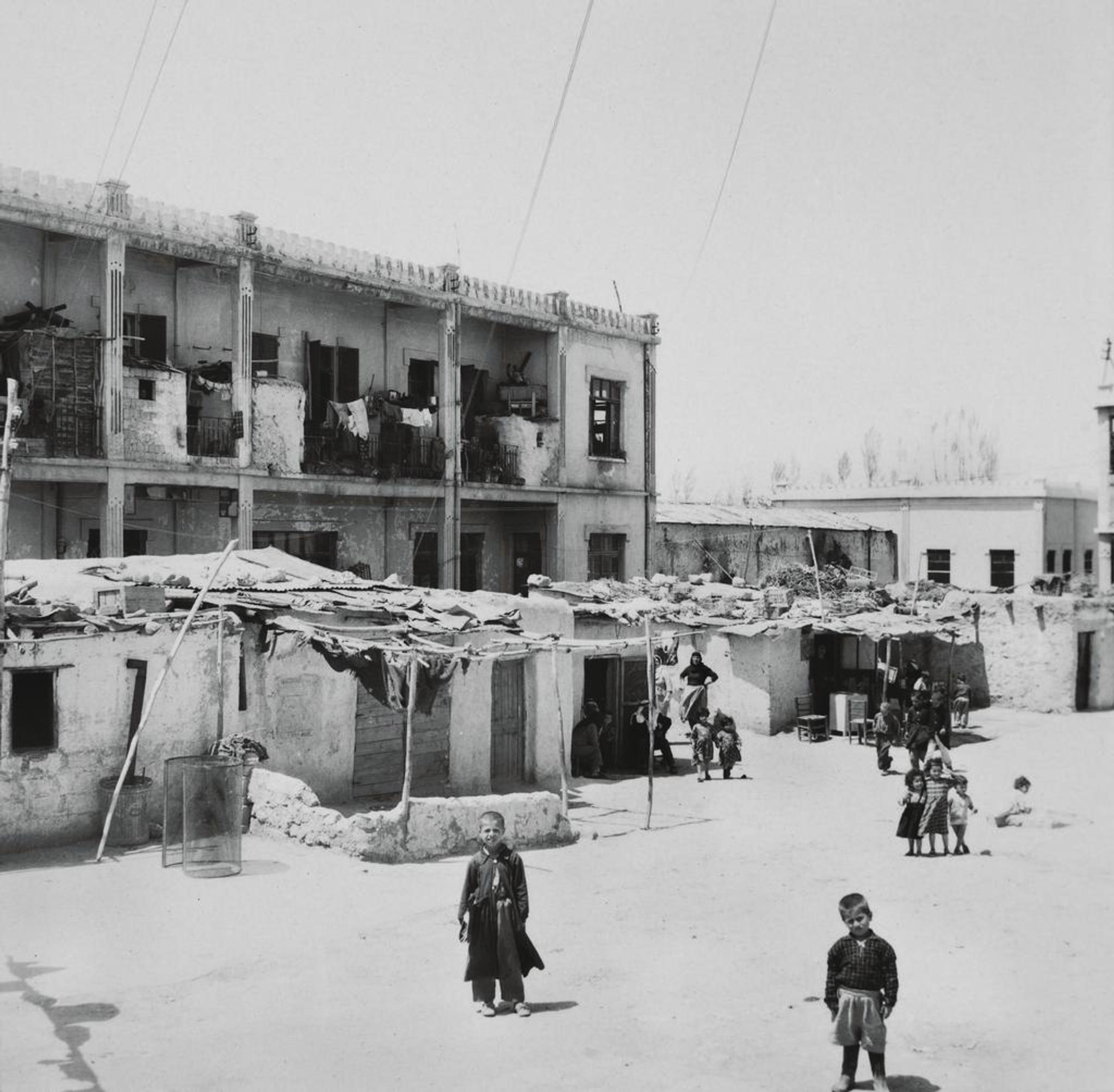 Children in front of a two storey residential building. Drying clothes hanging on and in front the building.