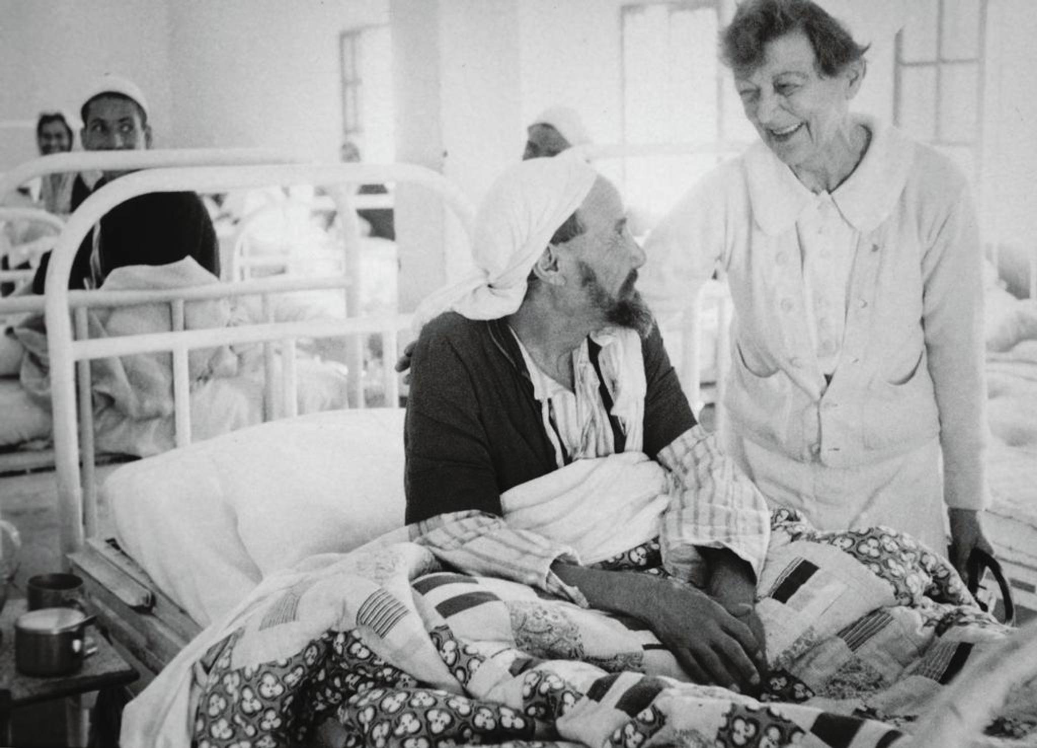 Nurse caring for man in hospital bed.