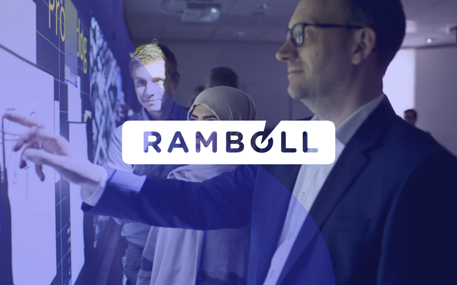 A picture of three people looking at a wall, with blue transparent overlay and the Rambøll logo over it