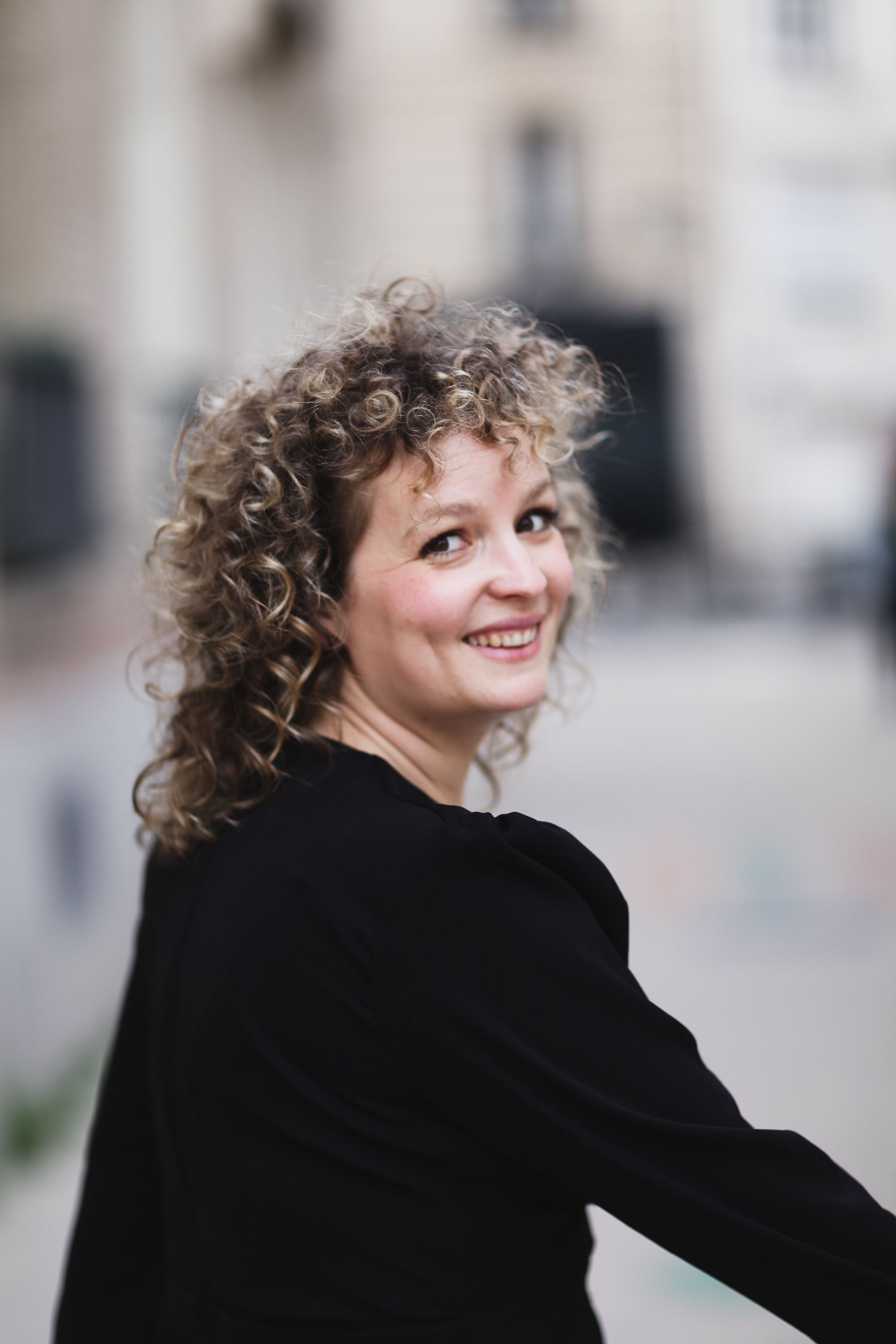 Sarah Calcine se retourne et sourit, en extérieur à Paris
