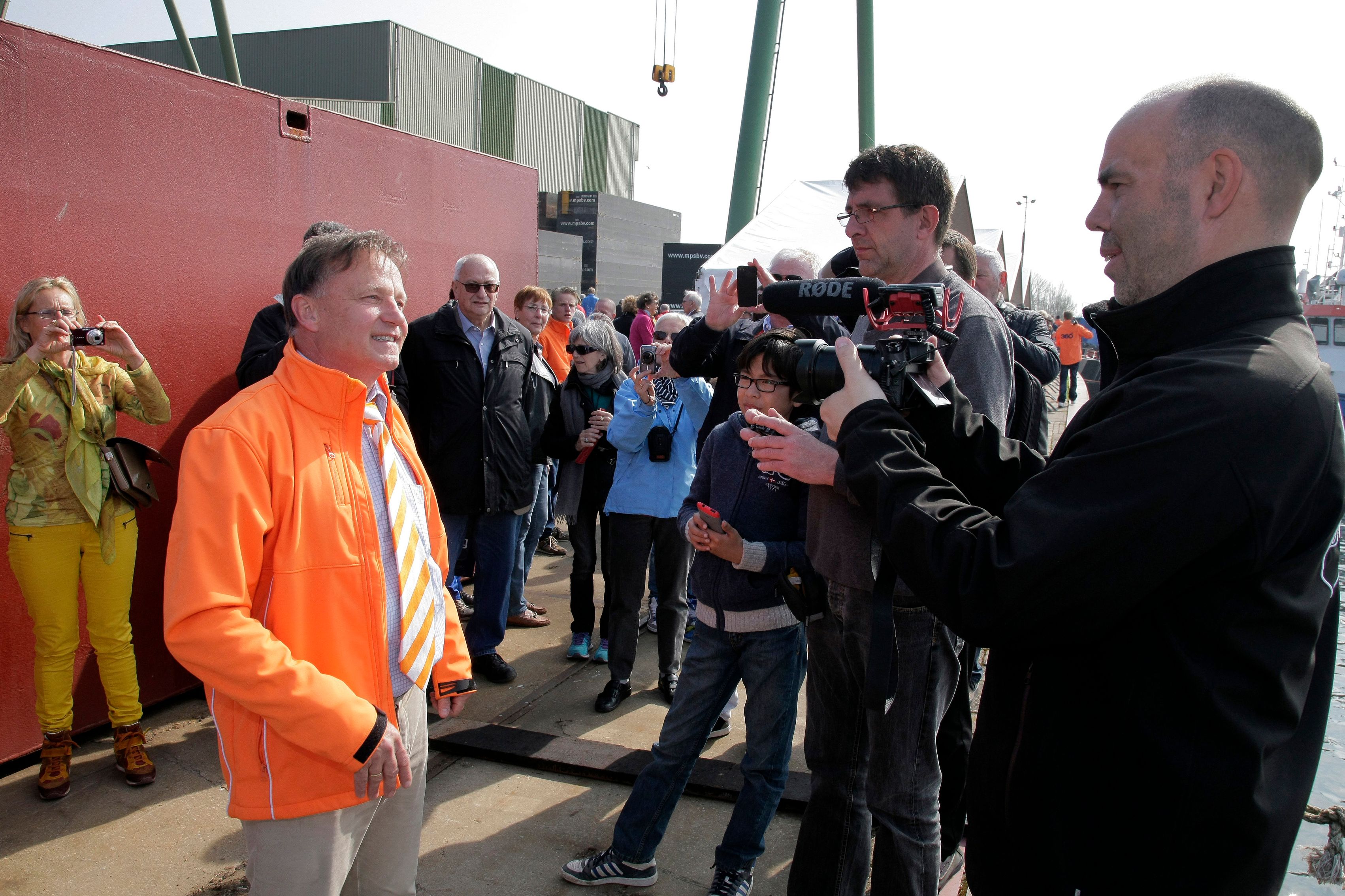 Een cameraploeg filmt een interview op de kade bij een tewaterlating van Elling, met een menigte voor de werf