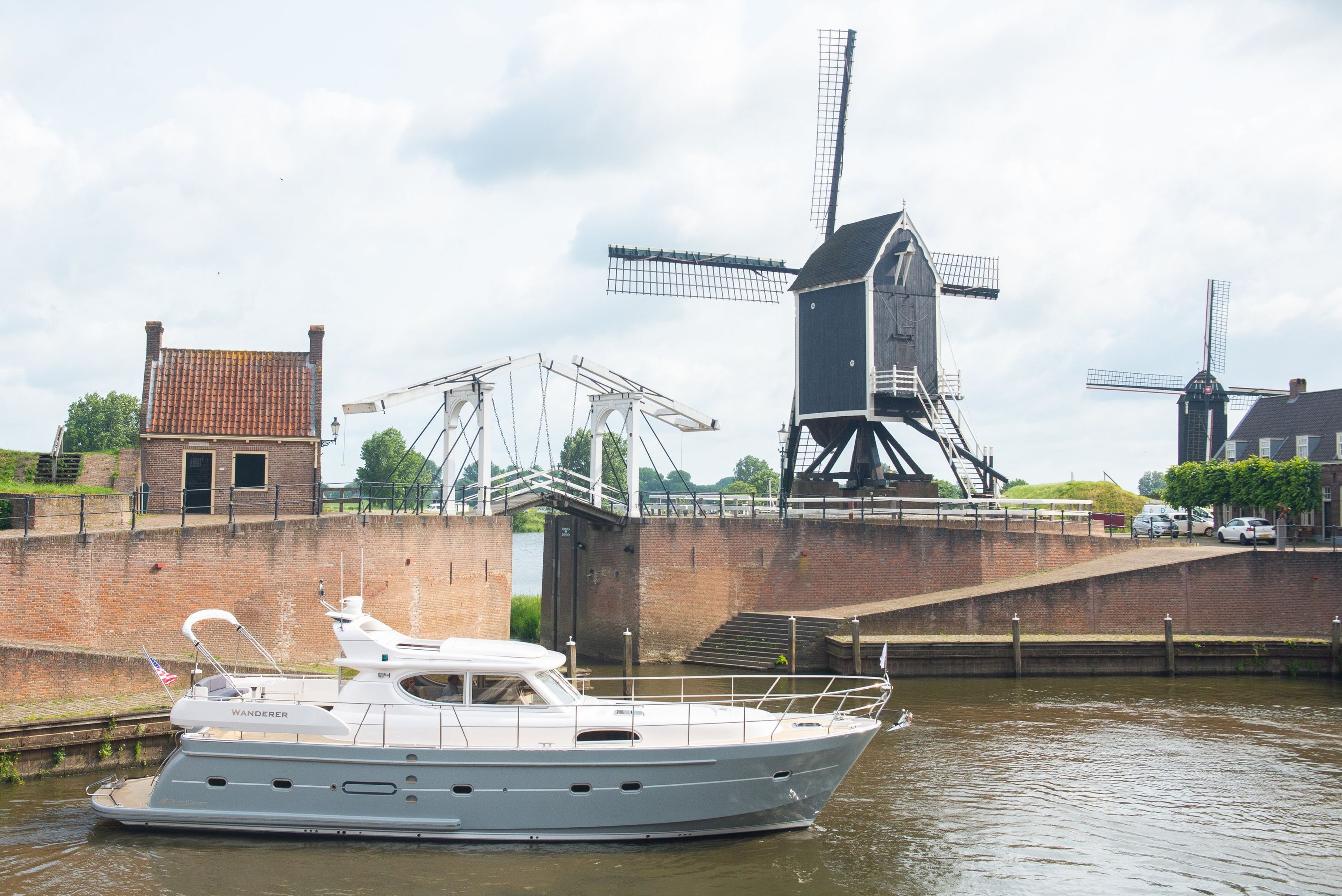 De Elling E4 vaart langs een molen en een witte ophaalbrug in een ommuurde Hollandse haven