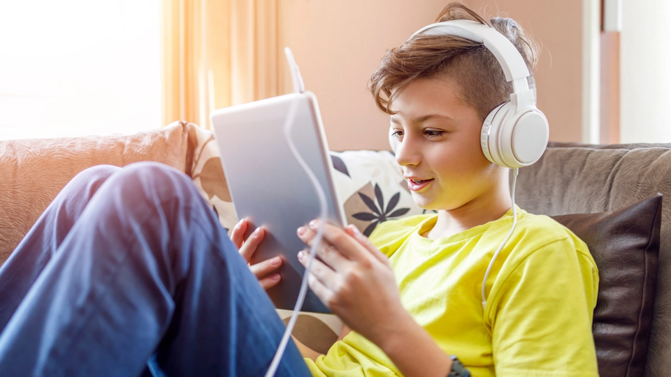 Boy using an iPad for an online tutoring session, comfortably learning from home.