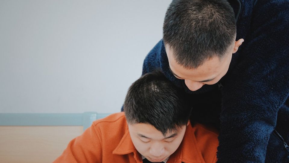 Parent sitting with child providing encouraging support during math practice