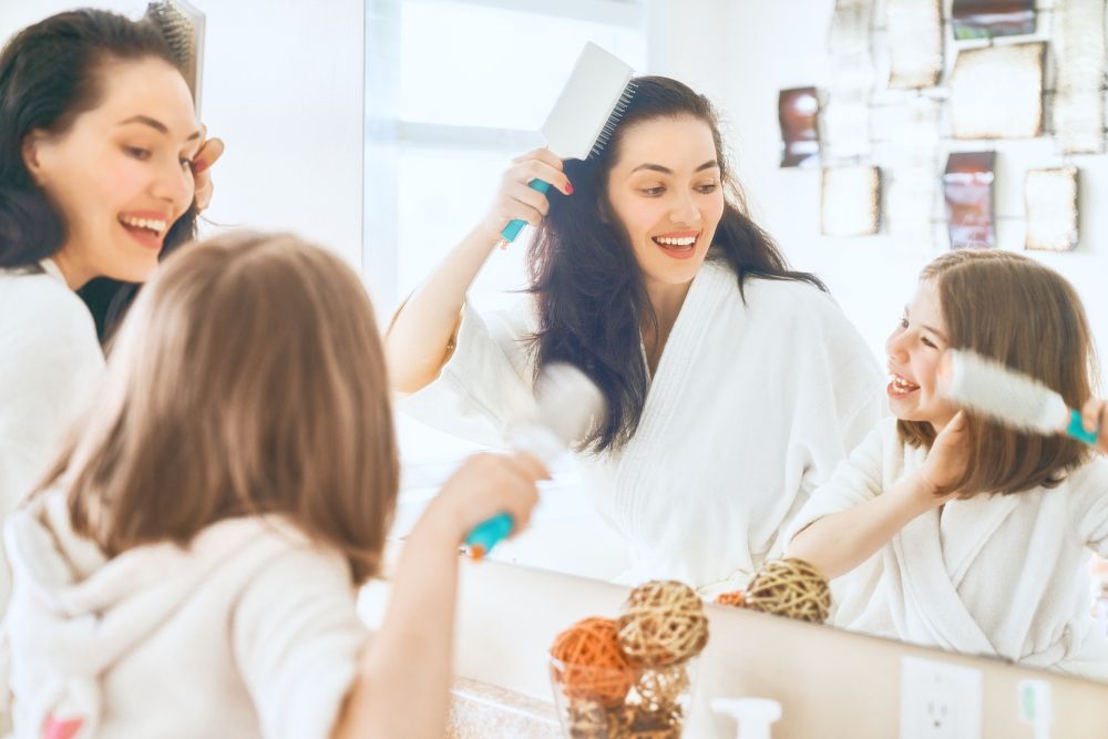 A mother and daughter brush their hair and teeth.