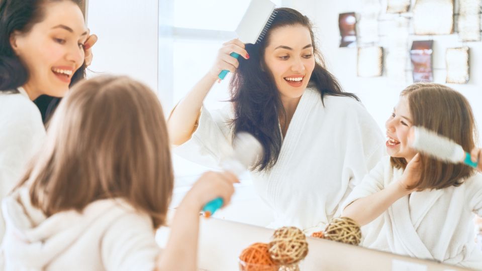 A mother and daughter brush their hair and teeth.