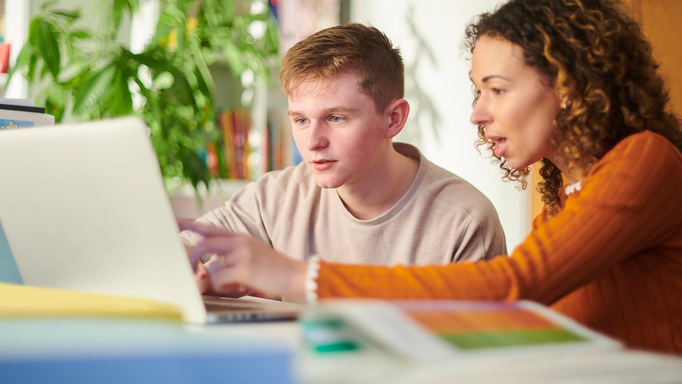 A dedicated tutor working one-on-one with a student, reviewing math concepts and providing personalized guidance on a computer.