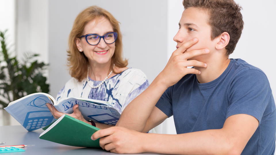A tutor working with a middle school boy on math.
