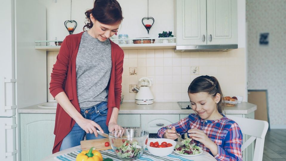 Parent helping child with homework at the kitchen table