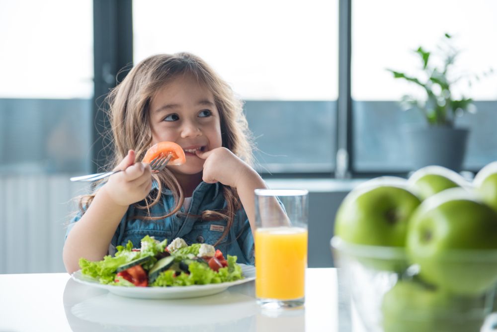 A young girl eats a healthy salad.