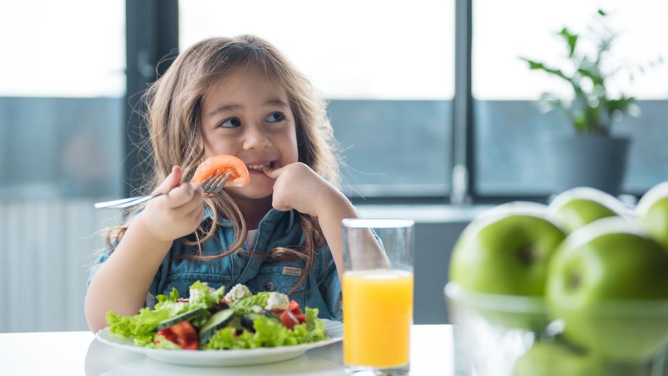 A young girl eats a healthy salad.
