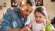 A father helps his young daughter with her homework.