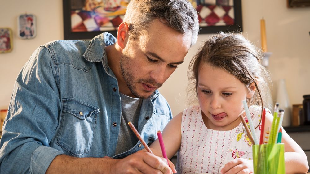 A father helps his young daughter with her homework.