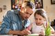A father helps his young daughter with her homework.
