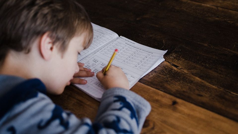 A frustrated child sitting at a desk with math worksheets, representing the challenges of traditional math tutoring