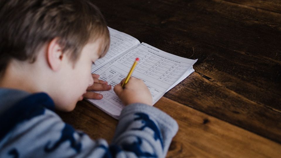 A frustrated child sitting at a desk with math worksheets, representing the challenges of traditional math tutoring