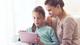 Mother watching daughter work on a tablet