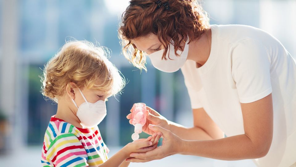 A mother sanitizes her son's hands.