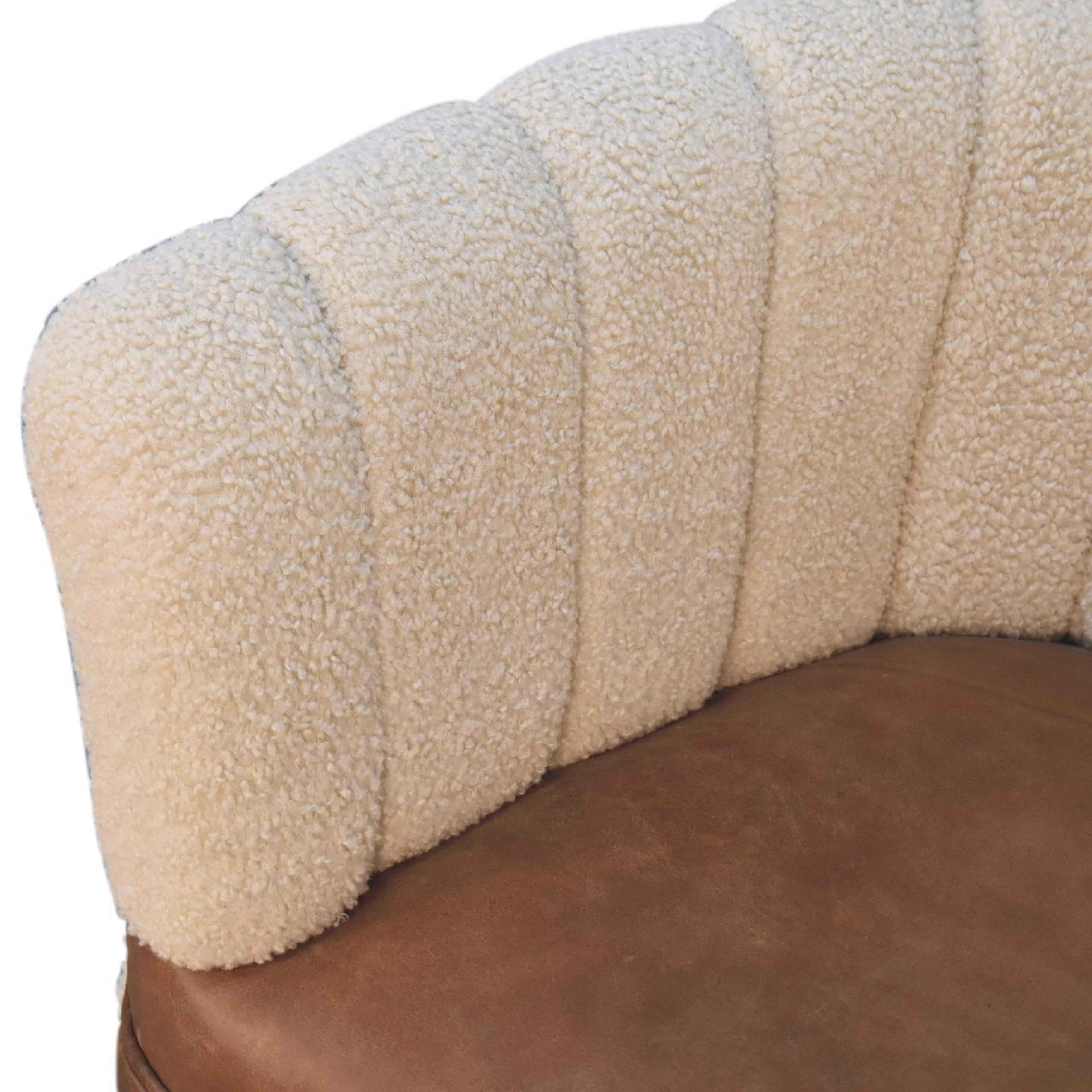 Fåtölj i gräddvit bouclé med sits i buffelläder och ben i nordisk stil