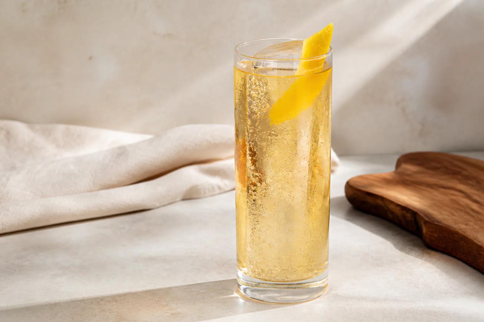 Tall Whiskey Highball with pale amber whiskey, clear ice, fine rising bubbles, and a clean lemon peel.