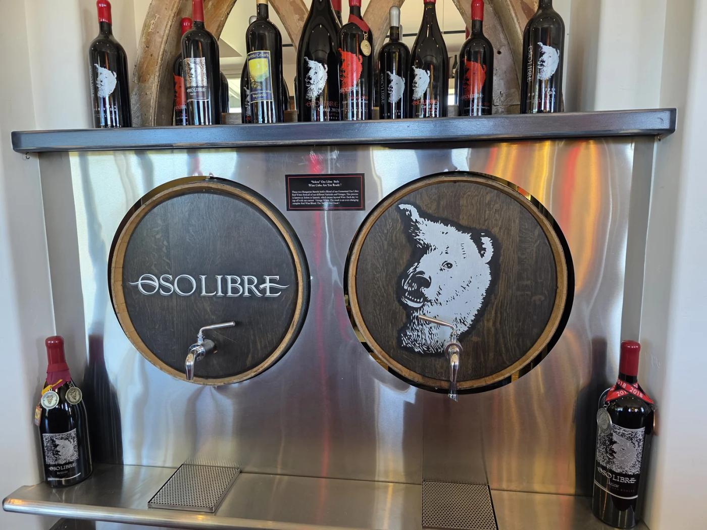 Oso Libre wine display with wooden barrel fronts, bottles, and the winery’s bear artwork