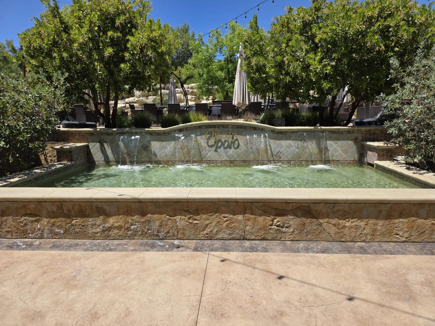 Stone fountain bearing the Opolo name, surrounded by greenery at the winery