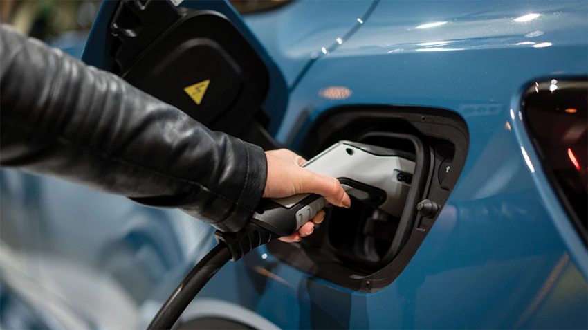 Hand plugging charger into an electric vehicle.