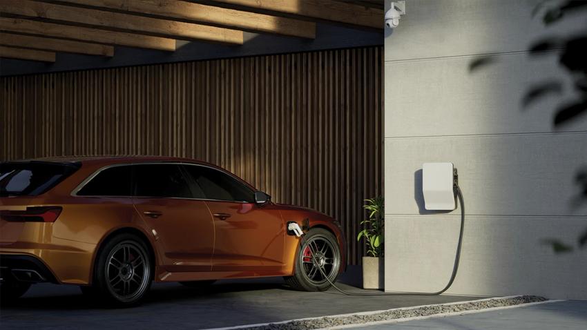 Person looking at their phone and plugging a charger into their EV.