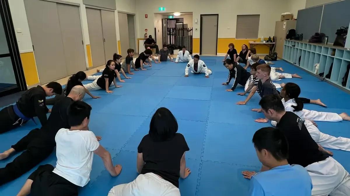 A class warming up in rows on the mats before training
